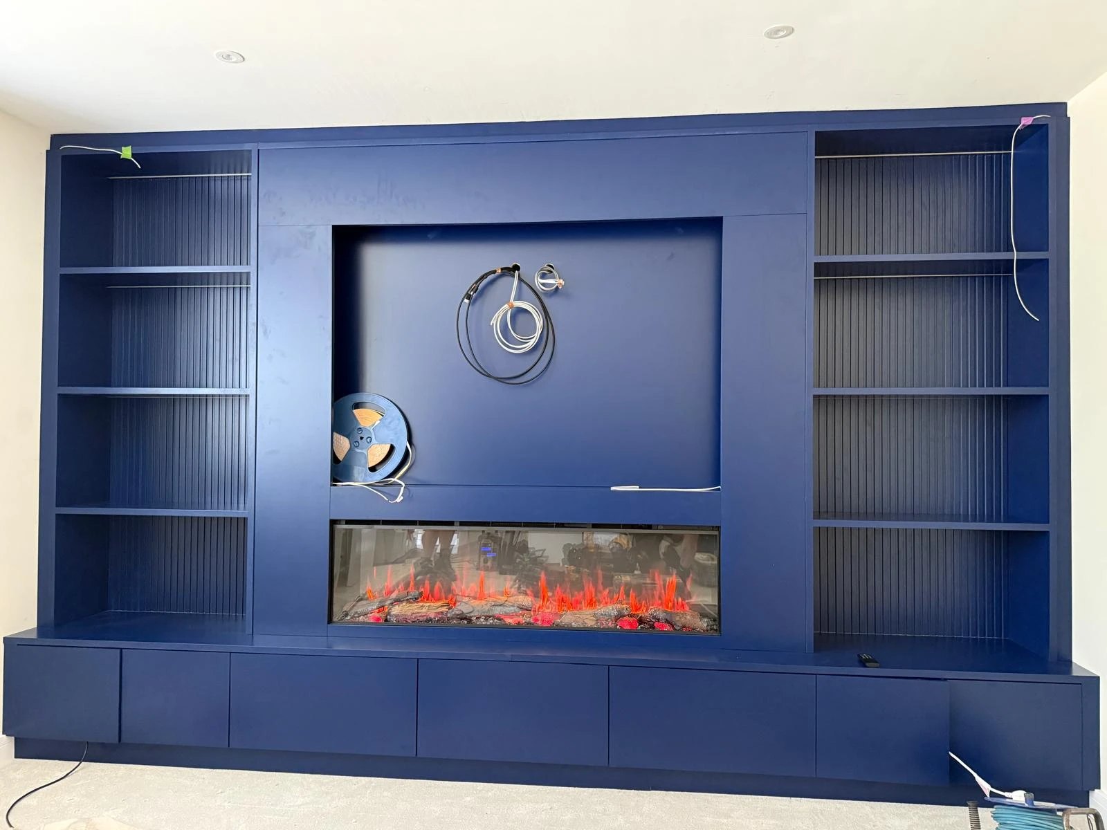 Blue media wall with fluted shelving and an inset fire, before the TV and lighting went in