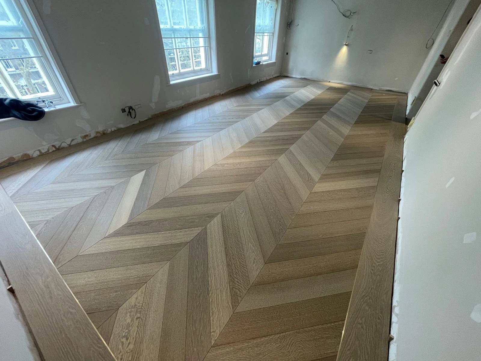 Grey oak chevron floor with a border, laid before the skirting goes on