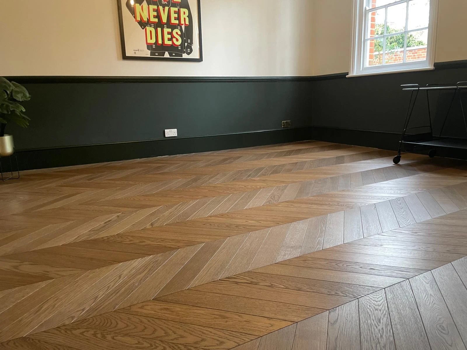 Smoked oak chevron floor in a dining room with dark green panelling