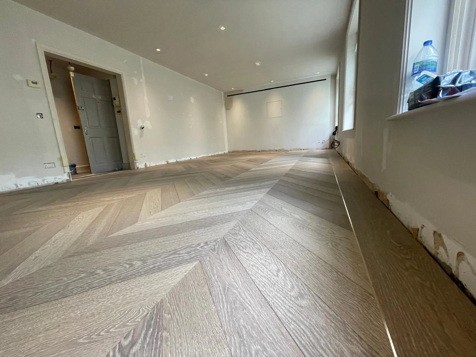Grey oak chevron floor laid through a long living room
