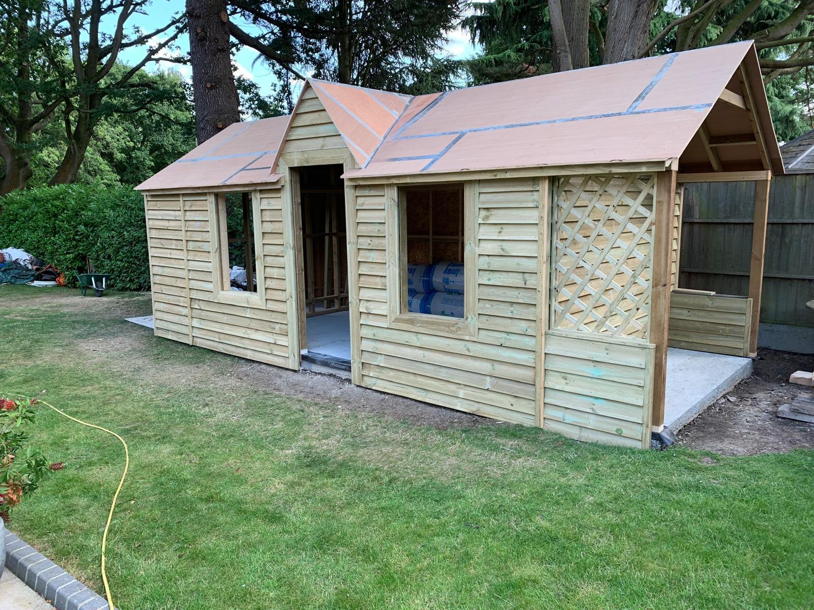 Timber garden building being clad, with a gabled porch