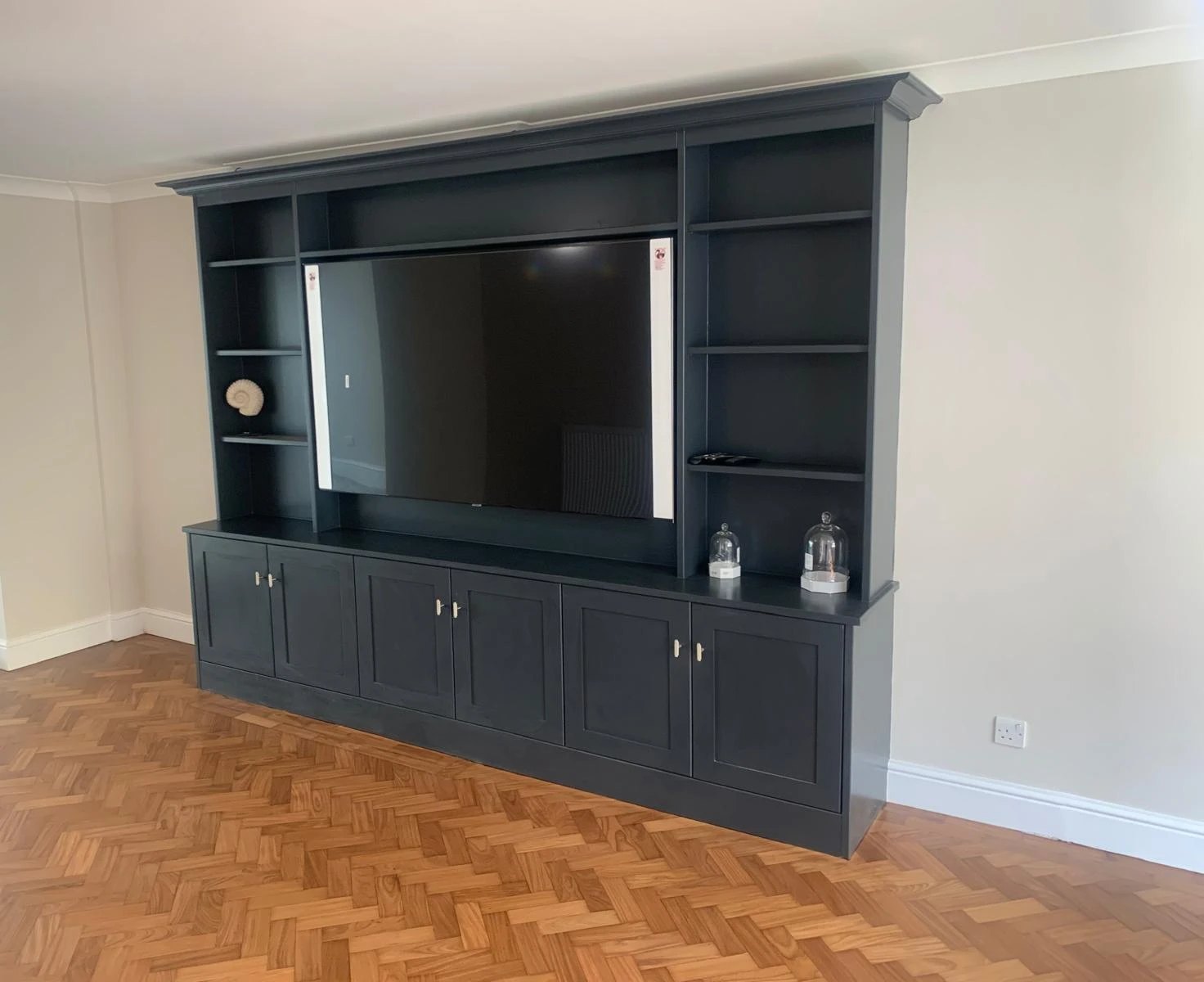 Navy painted media unit with shelving and shaker cupboards on a parquet floor