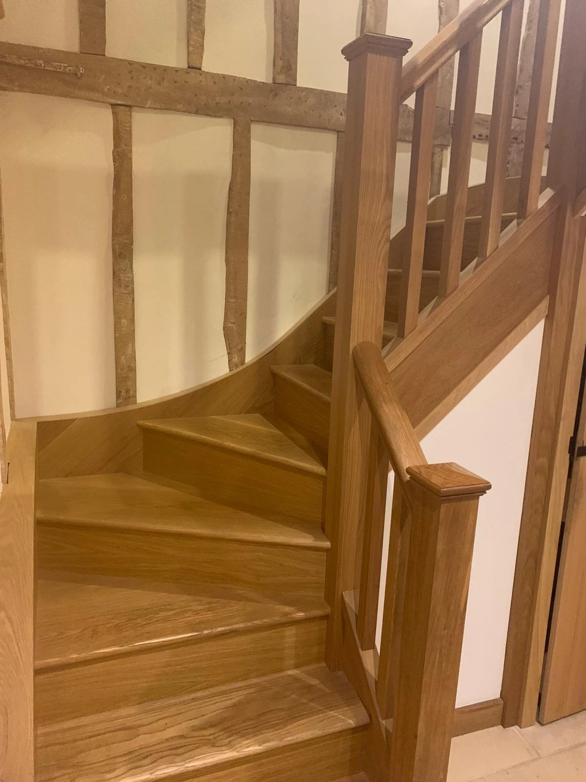 Oak winder staircase with square spindles against exposed timber framing