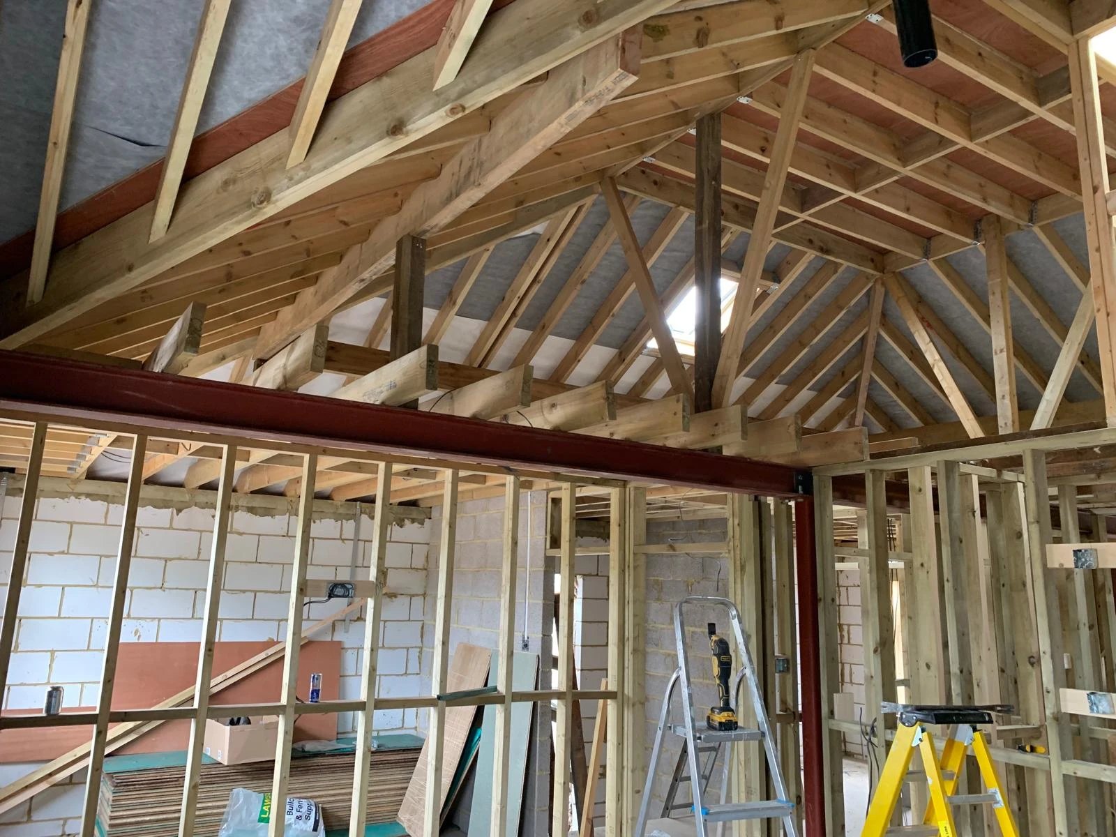 New roof framing carried on a steel beam over fresh stud walls