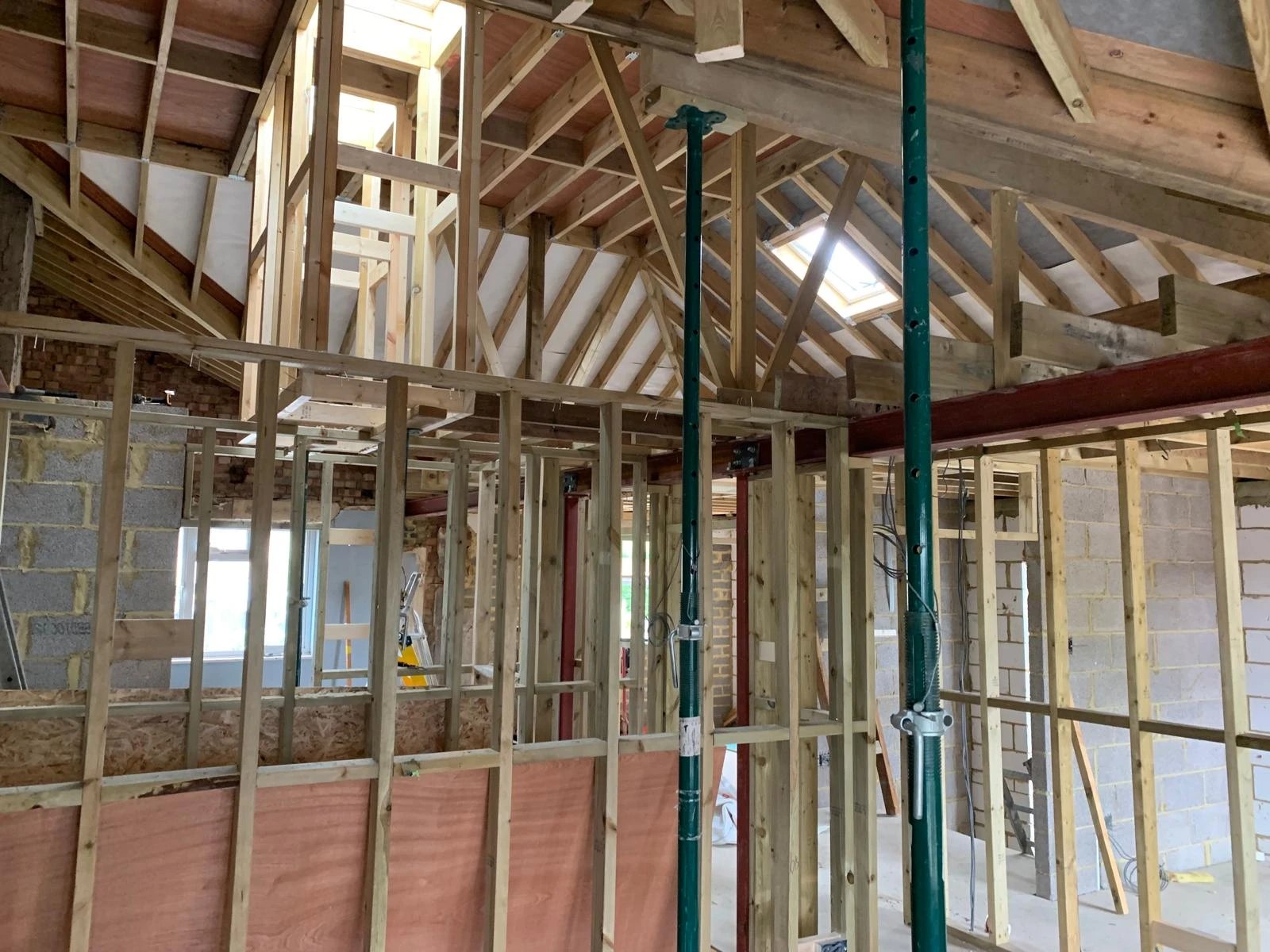 Stud partitions and roof framing going in, with props under a new steel