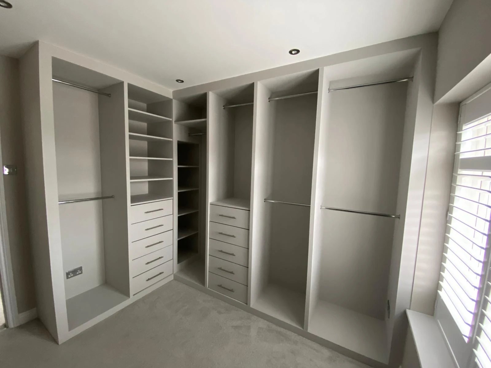 Fitted walk in wardrobe with hanging rails, shelves and drawers