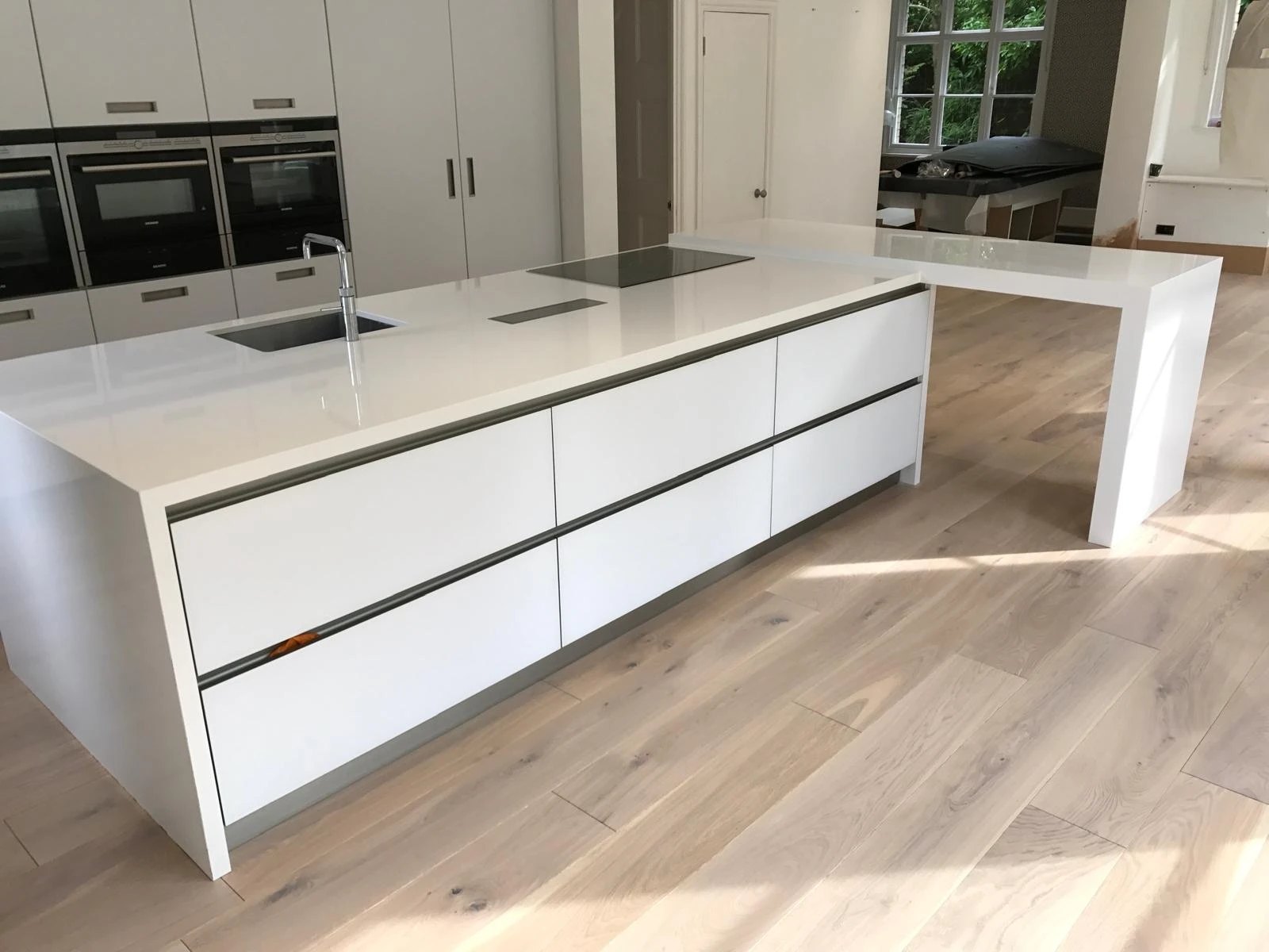 White handleless kitchen island with a quartz worktop and waterfall breakfast bar